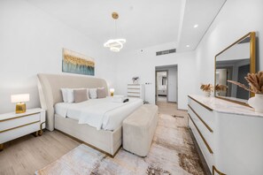 Ein modernes Schlafzimmer mit einem großen Bett, Nachttischen, einem Spiegel und einem Bild an der Wand.