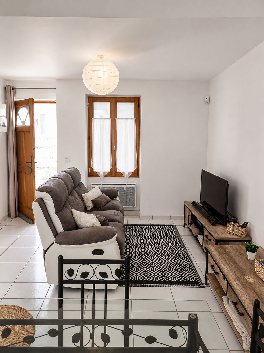 Un salon moderne avec un canapé, un téléviseur et un tapis à motifs.