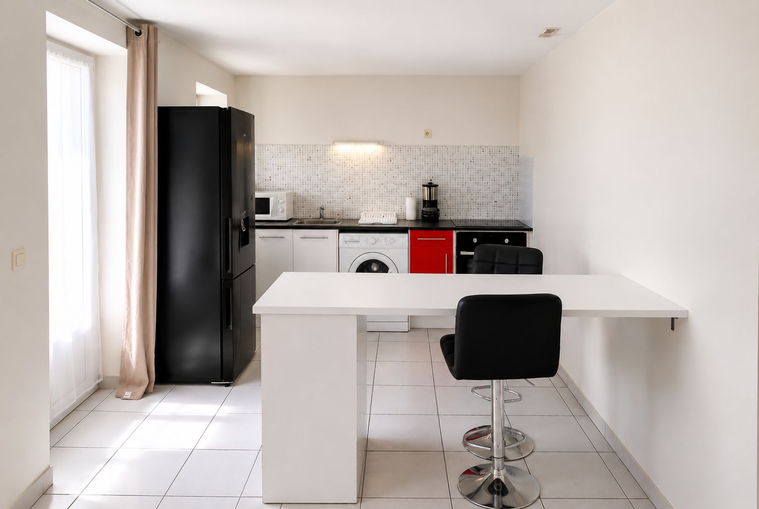 Een kleine keuken met een koelkast, magnetron, spoelbak en een wasmachine.