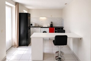 Een kleine keuken met een koelkast, magnetron, spoelbak en een wasmachine.