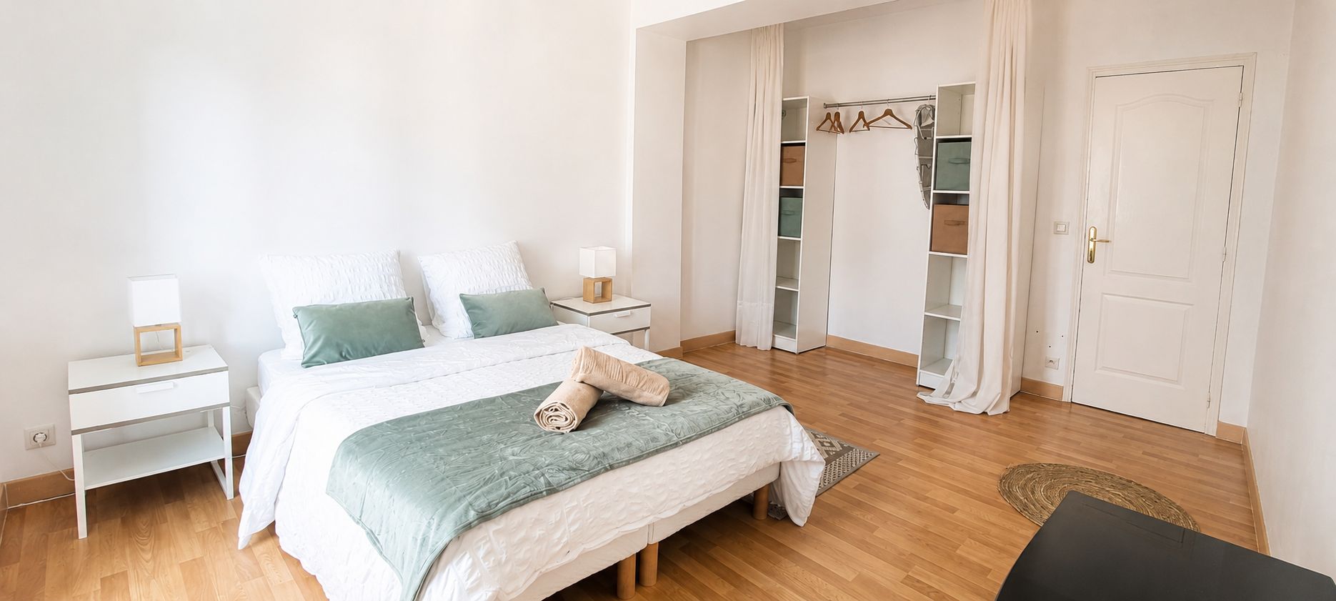 Une chambre à coucher avec un lit, des tables de chevet, une armoire et une porte.
