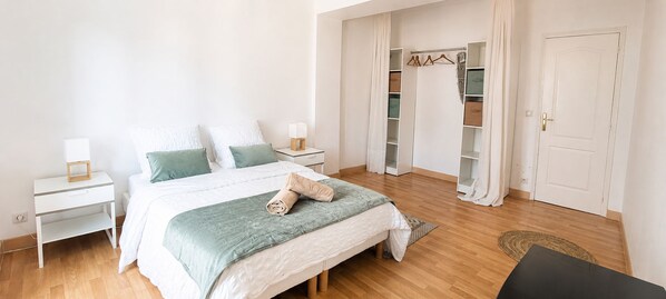 A bedroom with a bed, nightstands, a wardrobe, and a door.