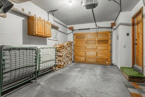 A garage with a wooden door, a stack of firewood, and a metal gate. - Just Renovated & Steps to Village! 2BR/2BA + Loft (Mammoth Lakes)