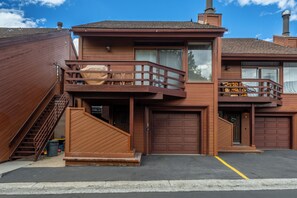 A two-story wooden house with a balcony, a garage, and a staircase leading to an upper level. - Just Renovated & Steps to Village! 2BR/2BA + Loft (Mammoth Lakes)