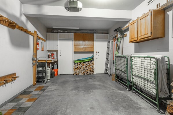 Ett rum med ett betonggolv, träskåp, en säng med en metallram och en brandsläckare på väggen.