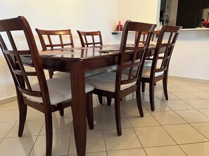 A dining table with six chairs, a kitchen area with a refrigerator, and a tiled floor. - Beautiful La Mancha Apartment + free parking (Carolina)