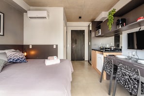 A modern hotel room with a bed, bedside table, and a kitchenette area. - Vrbo Property (São Paulo)