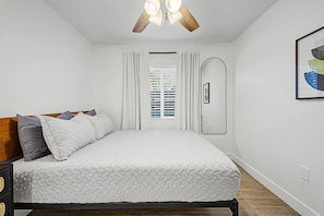 A bedroom with a bed, a ceiling fan, a window with blinds, and a framed picture on the wall. - Warm 2BR Phoenix Home | Private Patio + Parking (Phoenix)