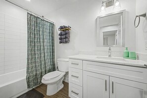 Un baño con cortina de ducha, inodoro, lavamanos y armario.