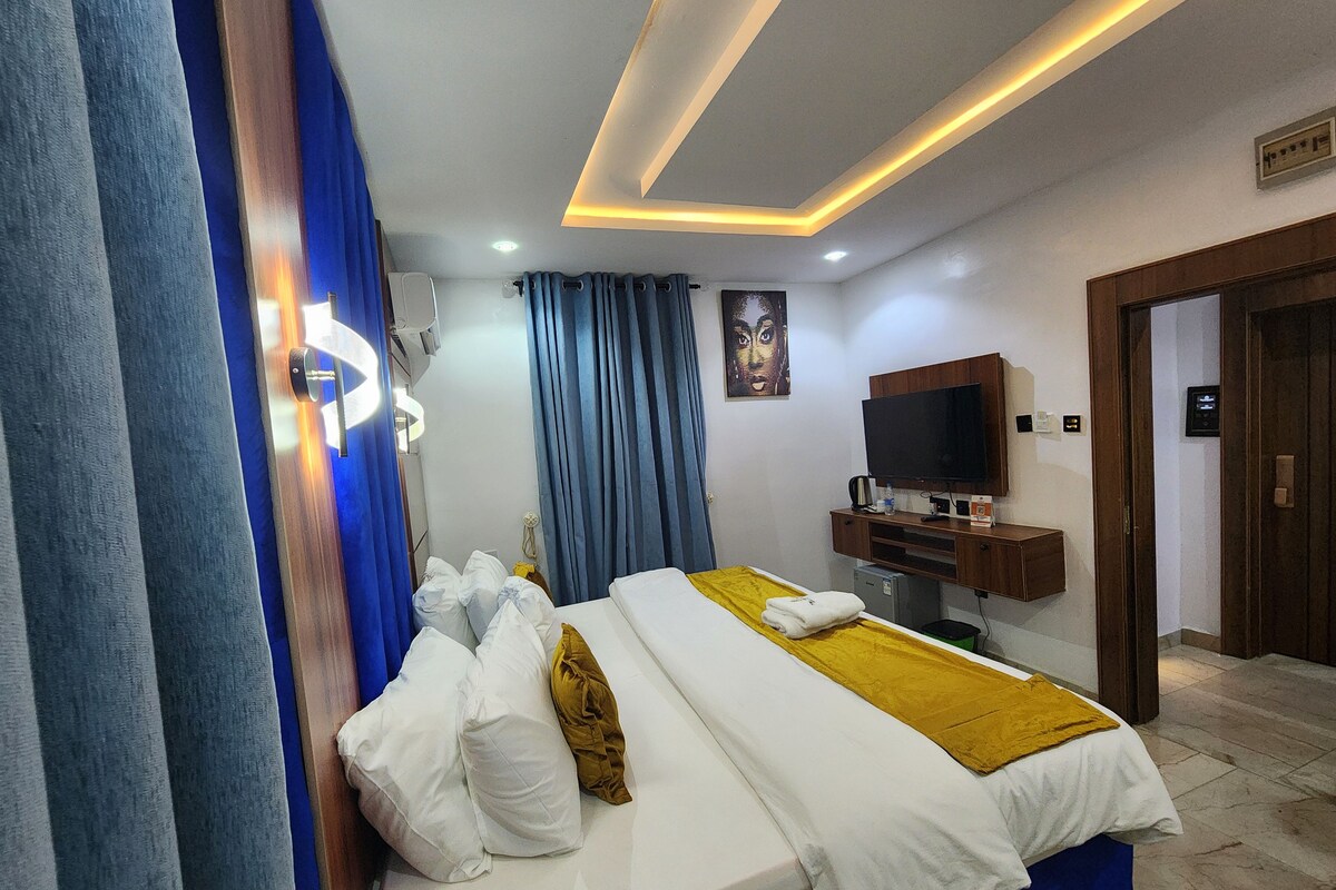 A hotel room with a bed, a television, a desk, and a bathroom.