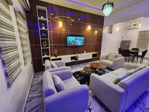 Una sala de estar moderna con un televisor de pantalla plana, asientos cómodos y un mueble decorativo.