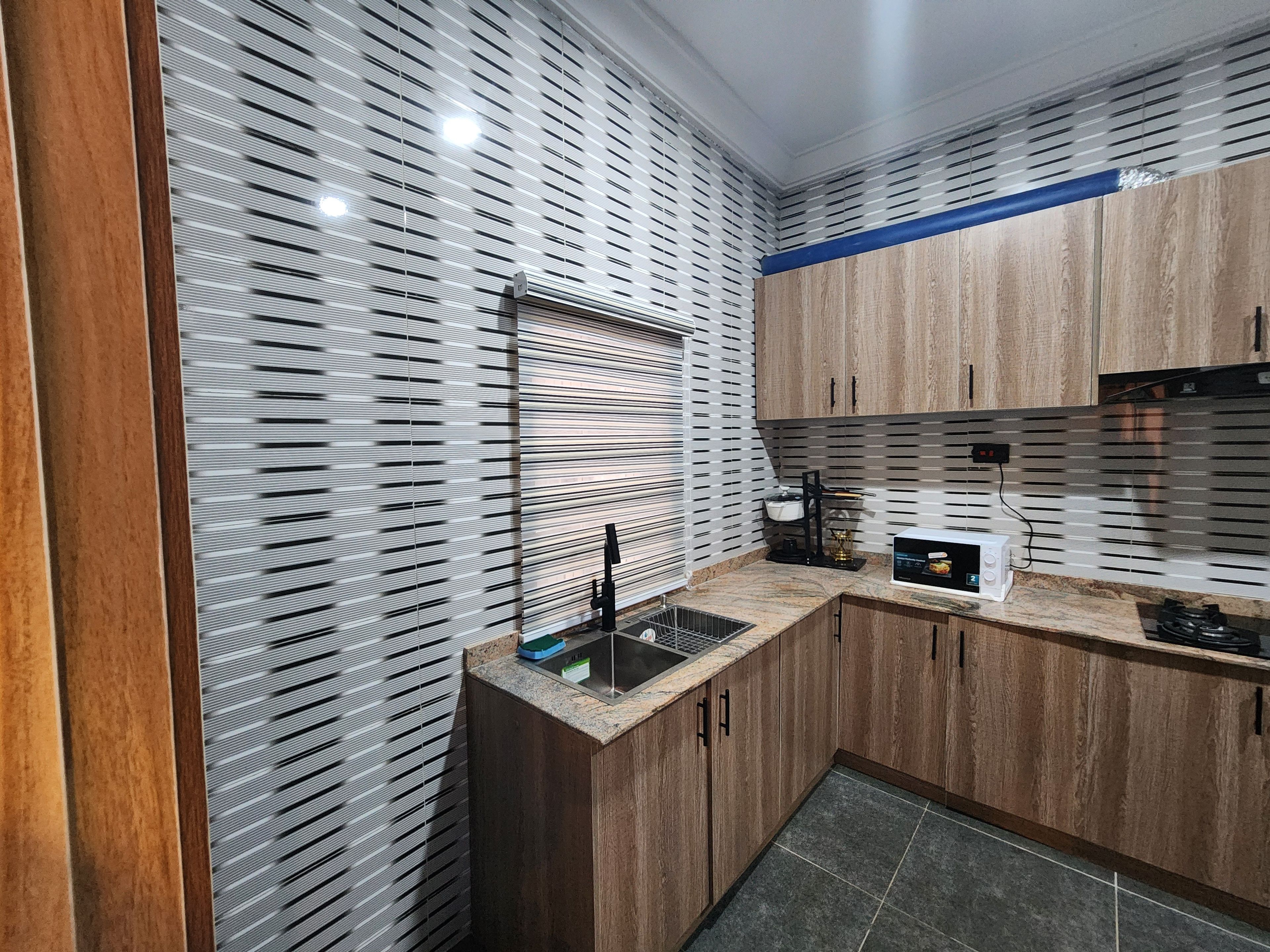 A modern kitchen with wooden cabinets, a stainless steel sink, and a microwave.