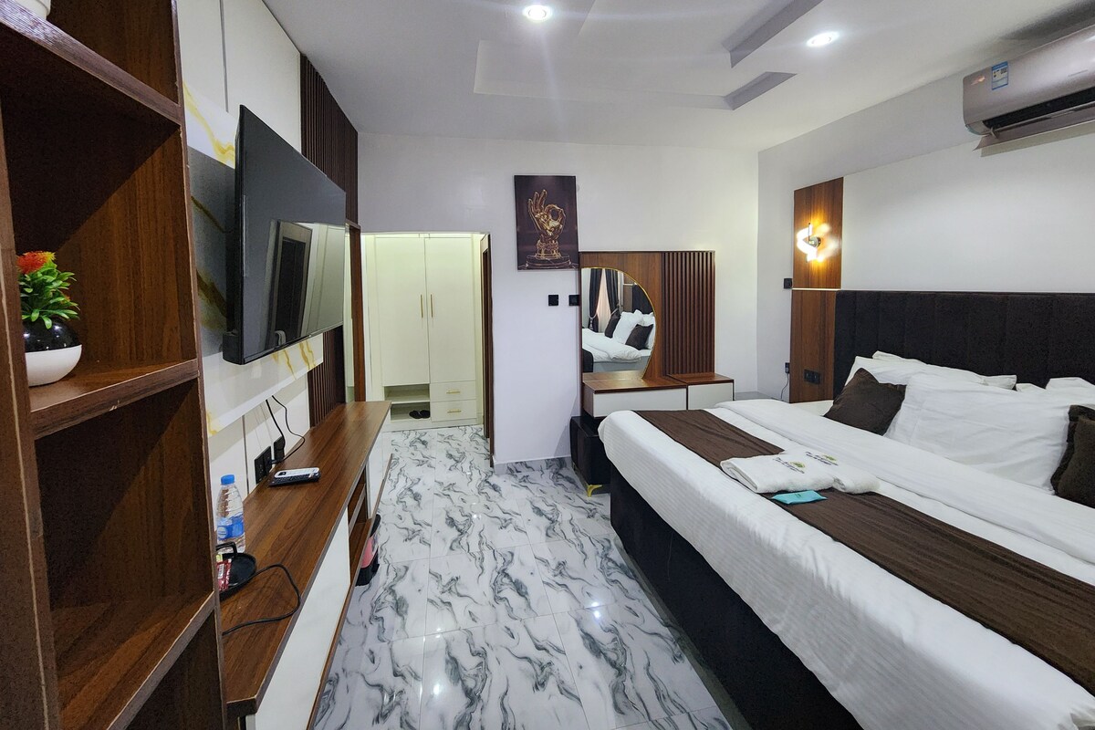 A hotel room with a bed, a TV, a desk, and a wardrobe.