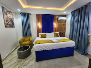 Una habitación de hotel con una cama, una silla, un televisor montado en la pared y un armario de madera.