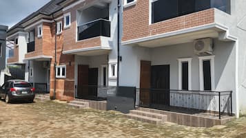 Un immeuble résidentiel à la façade en briques, doté de nombreux balcons et d’une allée pavée.