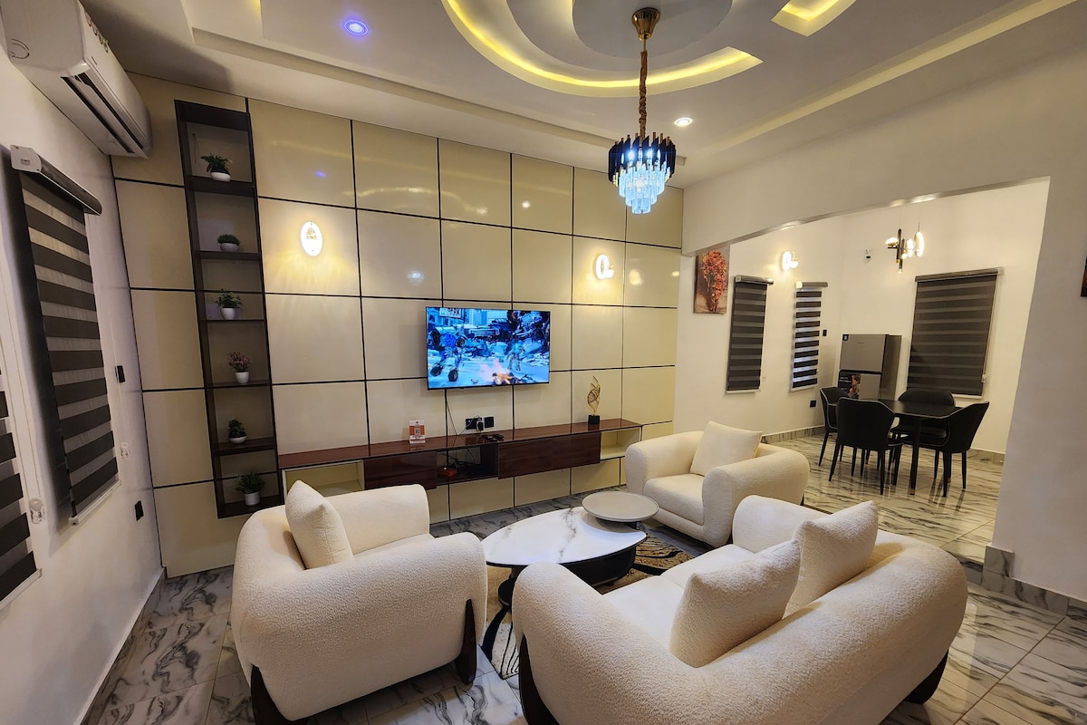 A modern living room with a flat-screen TV, plush sofas, a coffee table, and a dining area with chairs and a table.