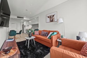 Un salon moderne avec un canapé, une table basse et un téléviseur.