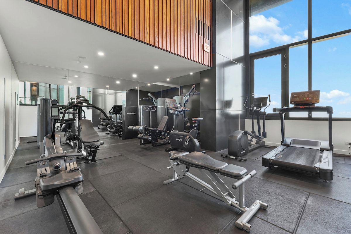 A gym with various exercise equipment, including treadmills, weight machines, and free weights.