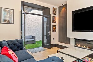 Ein modernes Wohnzimmer mit einer Couch, einem Flachbildfernseher, einem Kamin und Kunstwerken an den Wänden.
