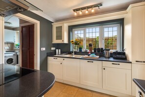 Eine moderne Küche mit Backofen, Spüle und Fenster mit Blick auf den Garten.