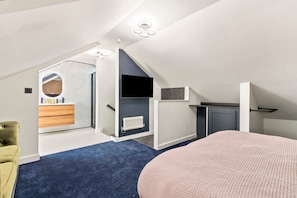 Ein modernes Schlafzimmer im Loftsstil mit schrägverdeckter Decke, integriertem Kleiderschrank, Heizkörper und einem großen Bett.