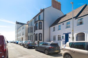 A street with parked cars and buildings, including a bowling club. - 3 Bedford House - Close to Town and Seafront (Tenby)