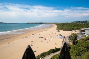 Ein Strand mit sandigem Ufer, einigen Sonnenschirmen und ein paar Personen.