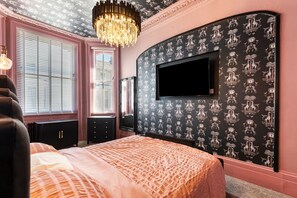 A bedroom with a large bed, a television mounted on the wall, and a chandelier. - 2 Bedford House - Close to Town and Seafront (Tenby)