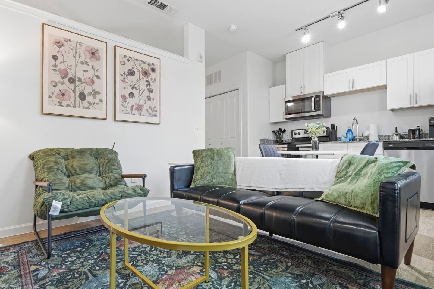 A living room with a green sofa, a black leather sofa, and a glass coffee table.