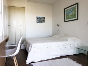 Ein Schlafzimmer mit einem Bett, einem Schreibtisch, einem Stuhl und einem Bild an der Wand.
