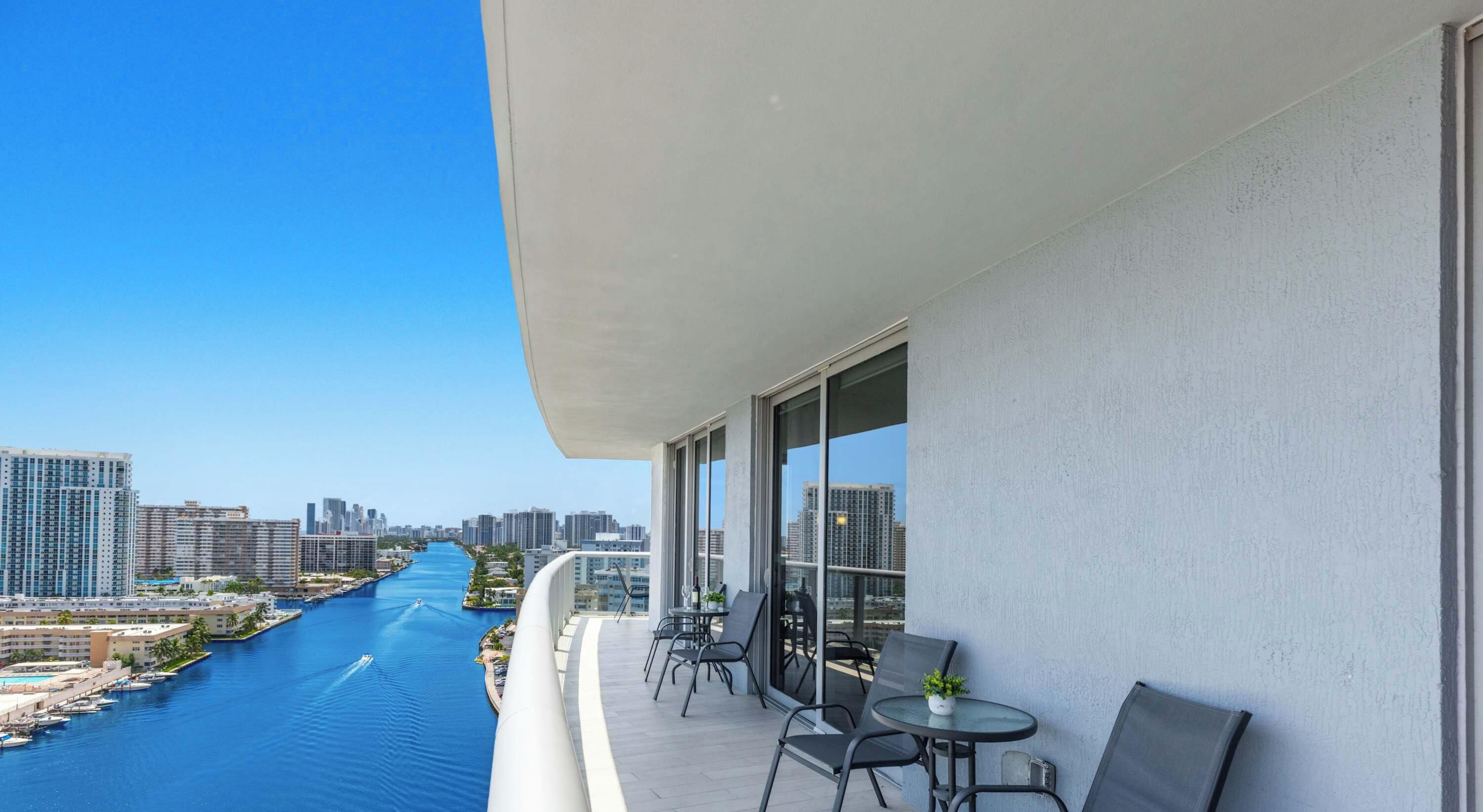 Ein Balkon mit Blick auf einen Fluss und die Skyline, ausgestattet mit Tischen und Stühlen.