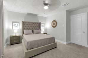 A bedroom with a bed, nightstands, a wall-mounted mirror, and a door. - SB Spring Getaway w/ Pool • Near I-45 • Sleeps 10 (Spring)