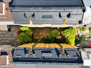 An aerial view of a building with multiple roof levels, including a flat roof with a yellow awning and a sloped roof with skylights. - Timeless Nordic | Quiet Street | Parquet | Lift (Helsinki)
