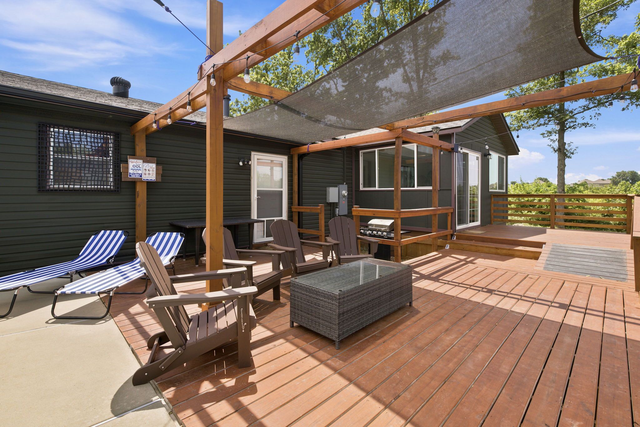 A deck with outdoor furniture, a grill, and a covered area with a mesh screen.
