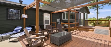 A deck with outdoor furniture, a grill, and a covered area with a mesh screen.