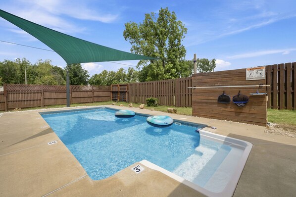 A swimming pool with a wooden deck, a shaded area, and a wooden fence. - Dave’s Place (Bentonville)