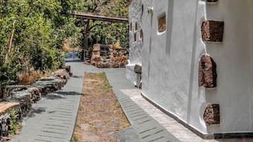 Un chemin mène à un bâtiment blanc doté de nombreuses fenêtres et d’un mur en pierre.
