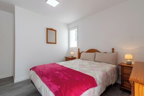 A bedroom with a bed, a bedside table with a lamp, a nightstand, a mirror, and a window. - Home2Book Beachfront Pool House La Garita (La Garita)