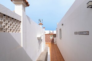 A narrow alleyway with white walls, a tiled floor, and a small door. - Home2Book Beachfront Pool House La Garita (La Garita)