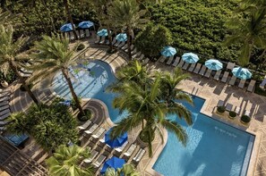 A pool area with lounge chairs and umbrellas, surrounded by palm trees. - Ocean View- Amazing 2 Bedroom Villa- Marriott's Oceana Palms- Full Resort Access (Riviera Beach)