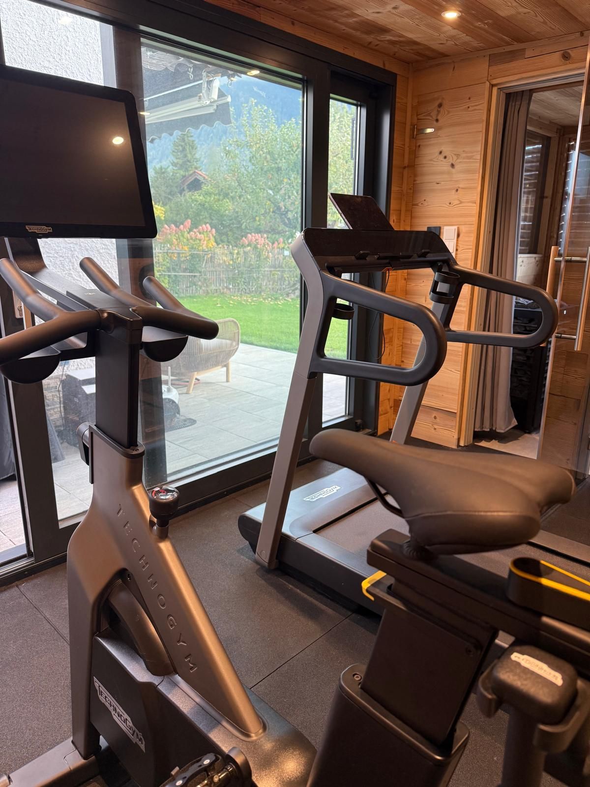 A gym with exercise equipment, large windows, and a view of the outdoors.