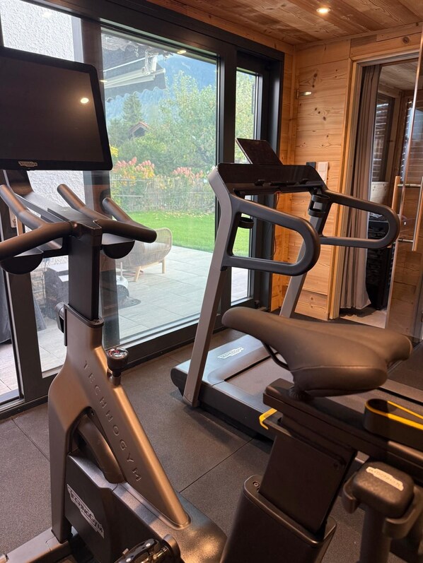 A gym with exercise equipment, large windows, and a view of the outdoors.