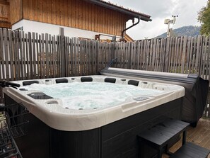 A hot tub with a wooden deck and a mountain view in the background.