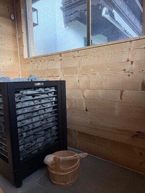 A Harvia refrigerator with a black exterior, a wooden wall, and a window.