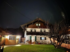 A two-story wooden house with a balcony, a small attached garage, and a well-maintained lawn.