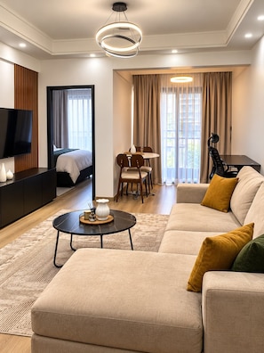 Une chambre d’hôtel moderne équipée d’un canapé, d’une table à manger, d’un téléviseur et d’un lit.