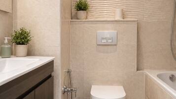 Un bagno moderno con lavandino, vaso da bagno, doccia e una piccola pianta sulla parete.