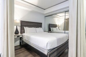 A hotel room with a large bed, a nightstand, a lamp, and a mirror. - Serene 2BR Yorkville (Toronto)