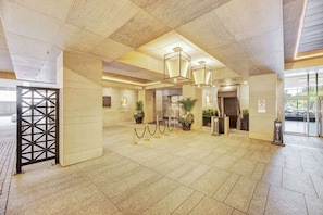 A spacious lobby with a tiled floor, a reception desk, potted plants, and a security checkpoint. - Serene 2BR Yorkville (Toronto)