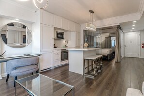 A modern kitchen with white cabinetry, a built-in oven, and a glass dining table. - Serene 2BR Yorkville (Toronto)